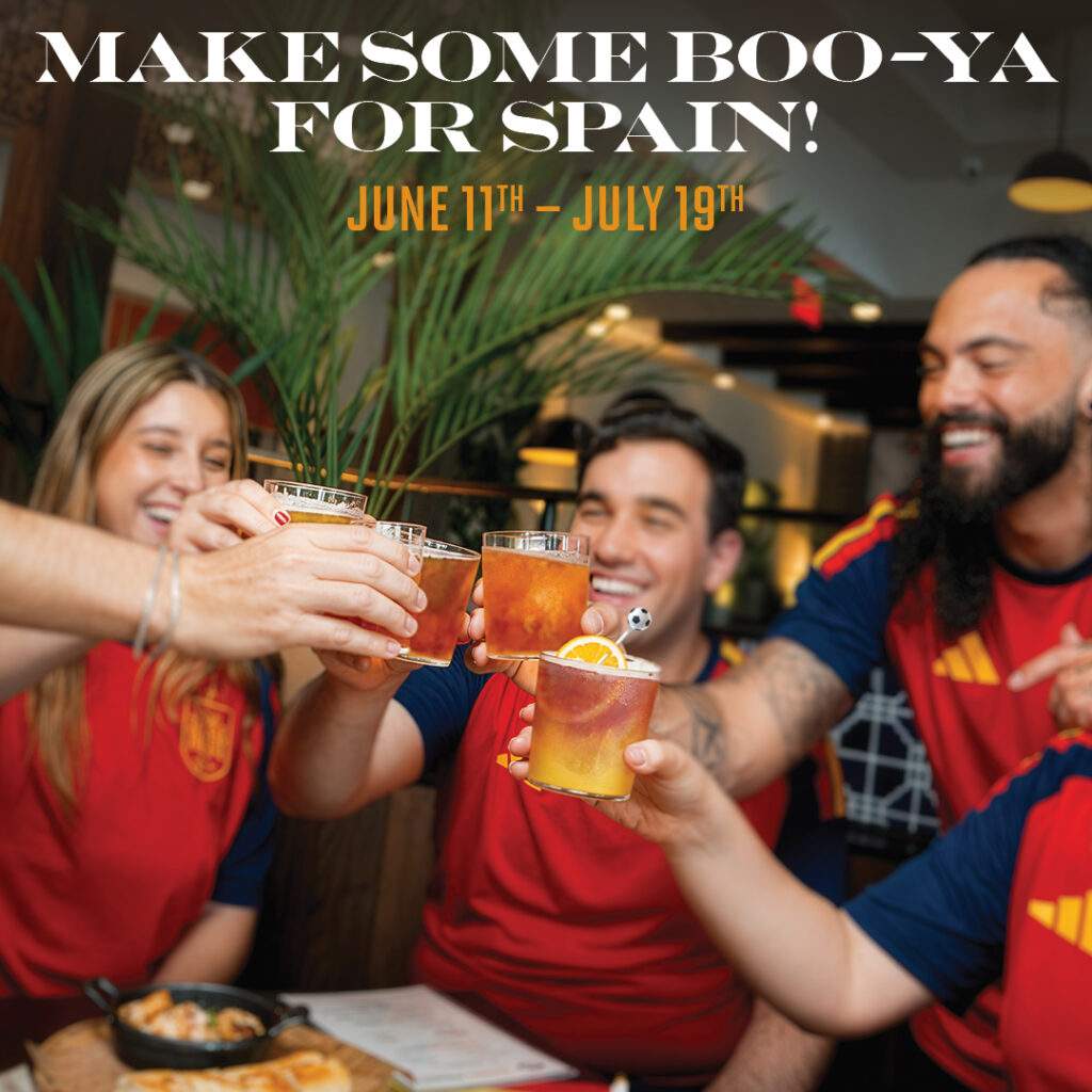 Group of fans wearing Spain jerseys cheering with drinks at Bulla Gastrobar, with the text “Make Some Boo-Ya for Spain! June 11th–July 19th.”