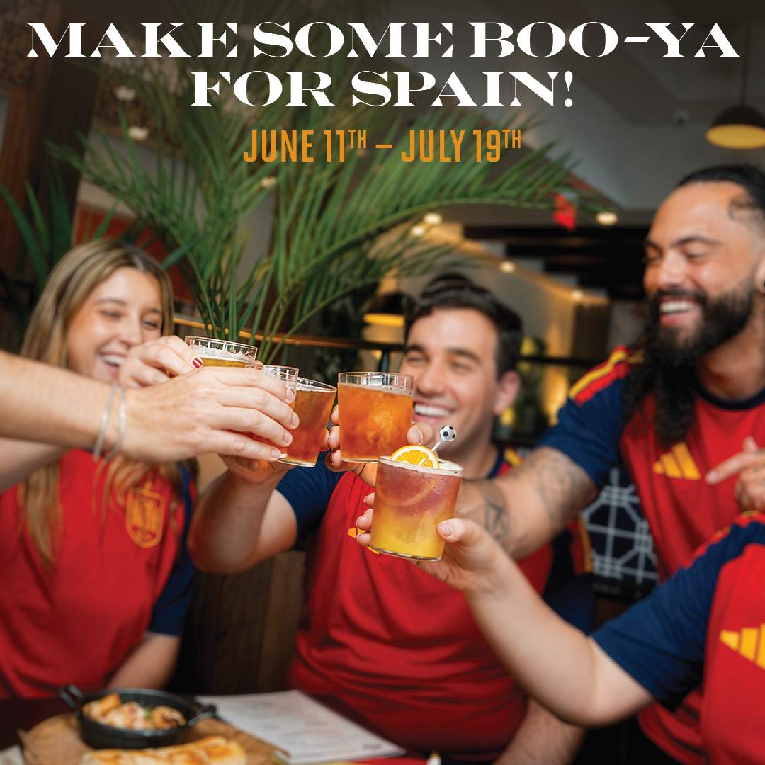 Group of fans wearing Spain jerseys cheering with drinks at Bulla Gastrobar, with the text “Make Some Boo-Ya for Spain! June 11th–July 19th.”